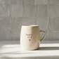 Caneca em cerâmica creme com salpicado multicolor e frase gravada Super avô em vermelho e azul com coração dourado, Tia Cila