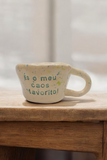 Caneca de cerâmica artesanal modelo Caetana com salpicado verde e frase gravada 'És o meu caos favorito' - Cerâmica Tia Cila.