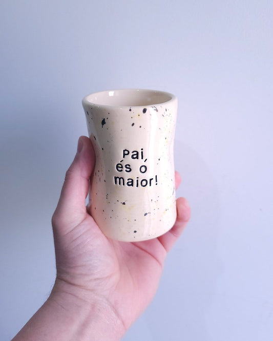 Copo alto Benedita da Tia Cila, cerâmica branca com salpicado preto e a frase gravada "Pai, és o maior!".