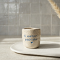 Copo de café artesanal modelo Inês, em cerâmica clara com salpicados azul intenso. Ao centro, a frase gravada "o melhor padrinho" com um pequeno coração, fotografado sobre uma superfície minimalista.