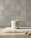 Copo de cerâmica artesanal modelo Inês, cor creme com salpicados ocre. No centro, a frase "Padrinho, adoro-te!" gravada em baixo relevo, fotografado num ambiente minimalista com luz natural.