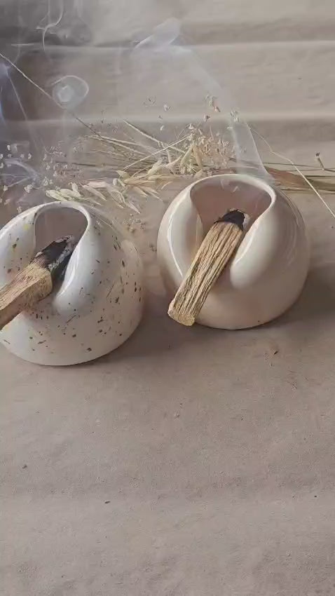 video-Dois queimadores de Pau Santo em cerâmica artesanal, um liso e outro salpicado, com paus de incenso natural a fumegar.